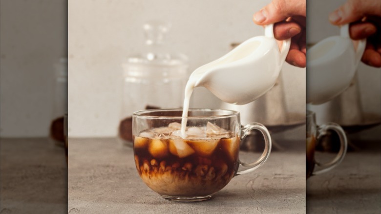 Milk pouring into a cup of cold brew coffee.