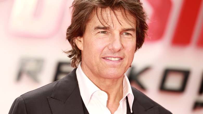 Tom Cruise poses in a black suit on an event red carpet