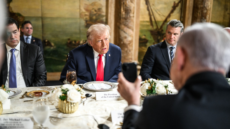 President Trump sitting at a dining table with other politicians waiting for food.