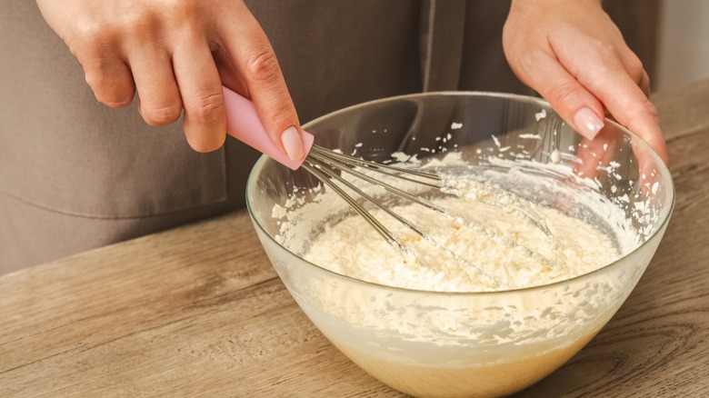 Person whisking cake batter in bowl