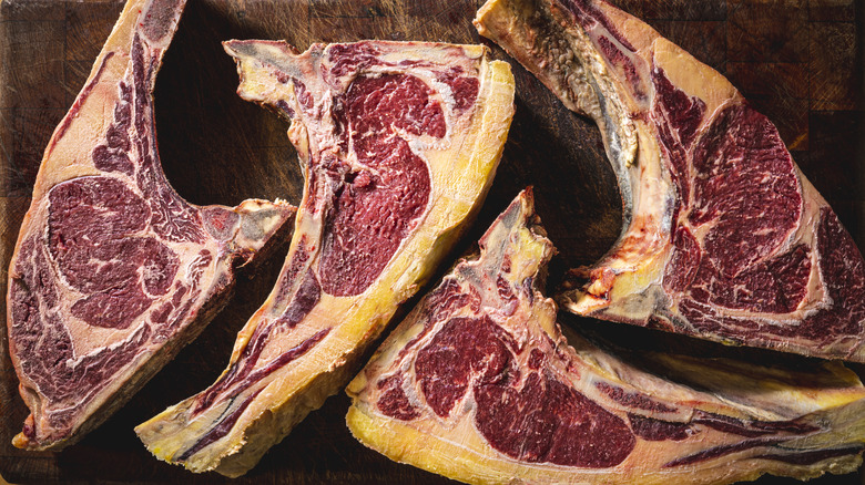 Four dry-aged pieces of meat sitting on a counter.