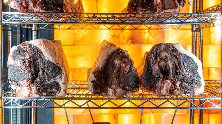 Cuts of beef dry aging in a fridge.