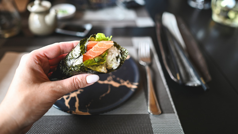Someone holding temaki, a sushi hand roll
