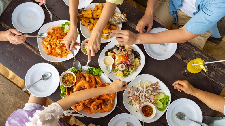 Hands serving from plates of food on table