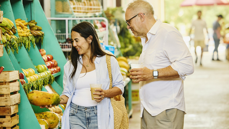 Two people selecting produce at an outdoor stall