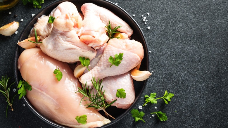 Raw chicken in a cast iron pan with herbs