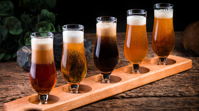 a beer flight in tulip glasses sitting in a wooden flight board