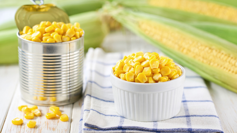 An open can of overflowing corn and a small ramekin containing corn