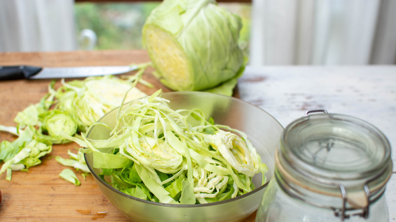 Sliced cabbage sits in a glass bowl on a table.