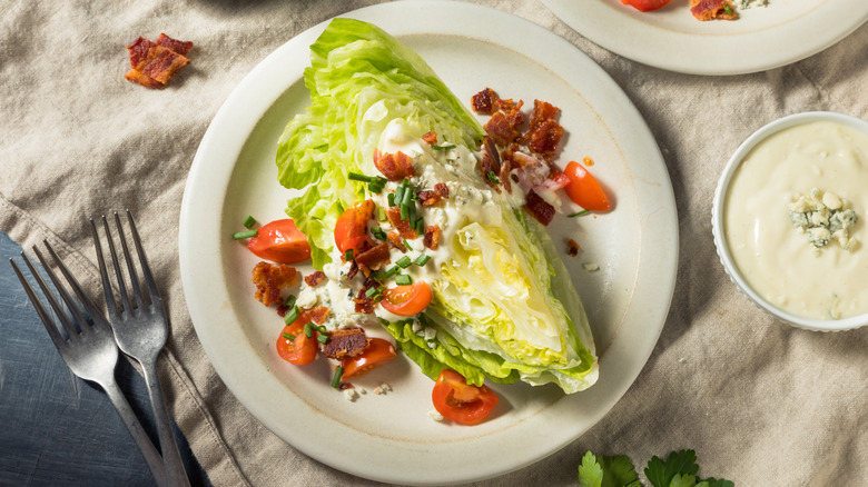 Top view of wedge salad with bacon, blue cheese dressing, and cherry tomatoes