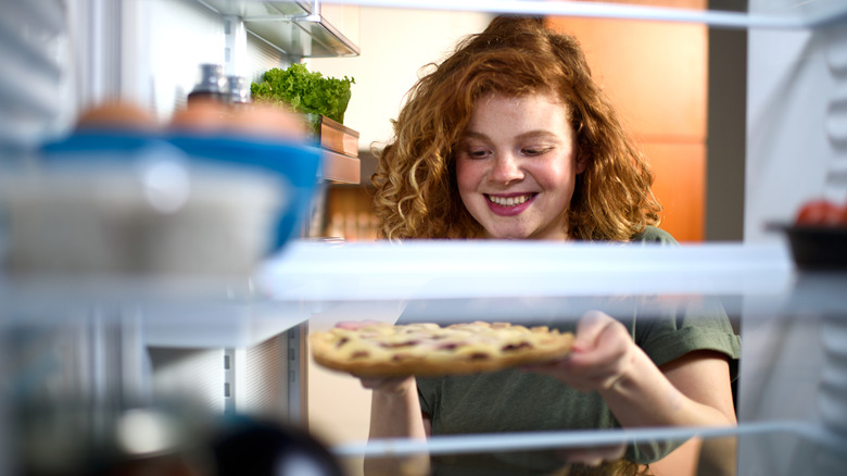 A woman places a pie in a fridge