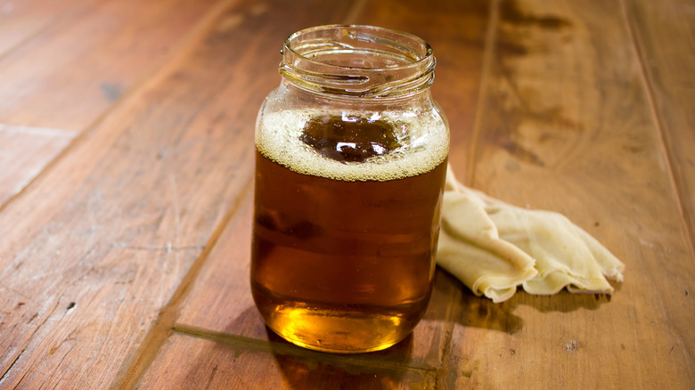 A Mason jar of used cooking oil on wooden table