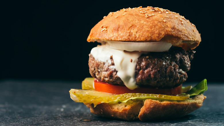 Burger with mayo, tomatoes, pickles, onion, and lettuce