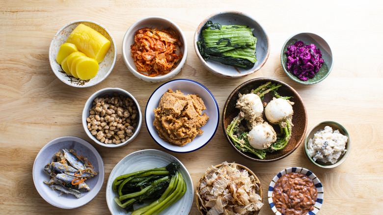 Small bowls of Asian condiments including kimchi, ginger, miso, and bonito flakes