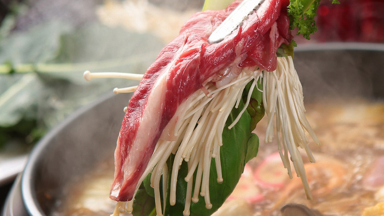 Raw meat being dipped into Japanese hot pot broth