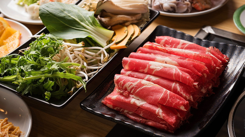 Fresh produce and thinly sliced meat on platters for shabu shabu
