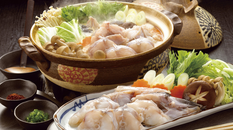 Traditional Japanese hot pot with a variety of raw meats and vegetables on a plate and in the pot