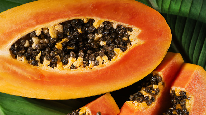 Orange papaya halves with seeds and green leaves