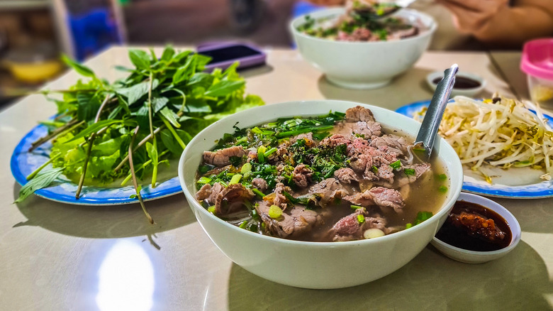 Bowl of pho with garnishes and condiments