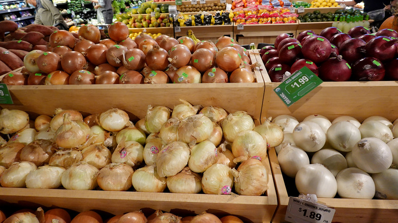 red, white, and yellow onions for sale in a supermarket