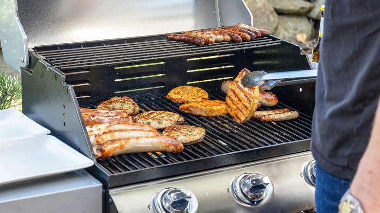 Person grilling meats on gas grill