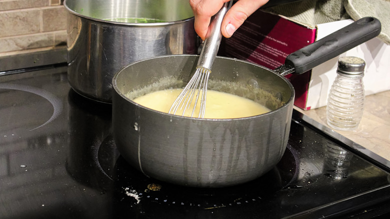 Hand whisking a pot of gravy on a stove
