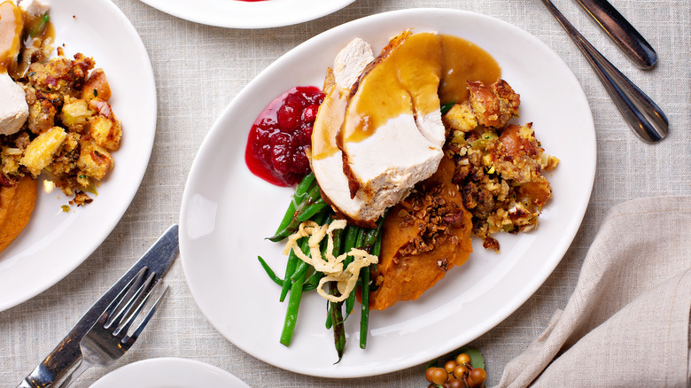 Thanksgiving plates with turkey, gravy, stuffing, green beans, and cranberries