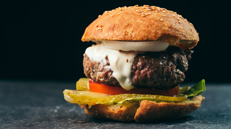 Burger with mayo, tomatoes, pickles, onion, and lettuce