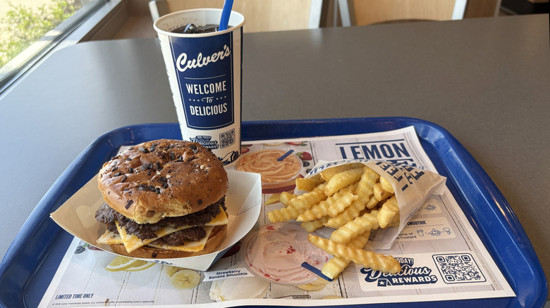 Burger meal with fries and a drink on Culver's tray inside a store.