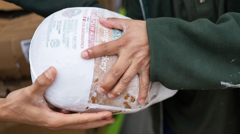 Person handing frozen turkey to another