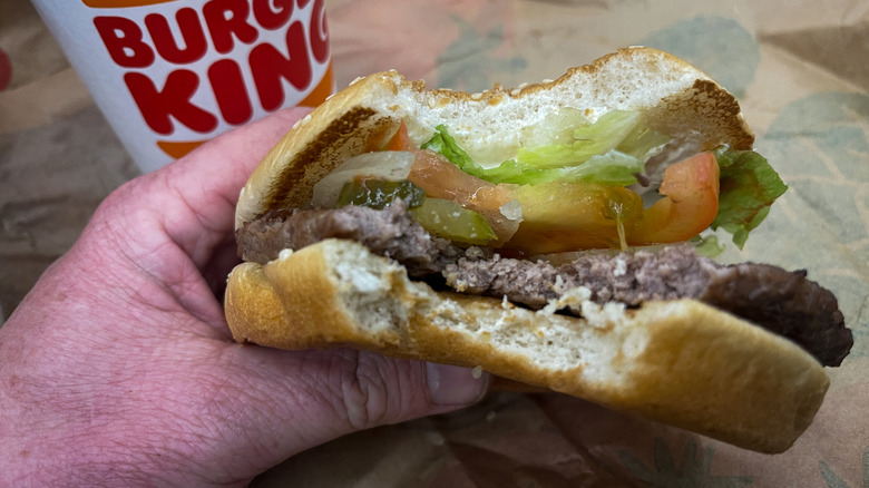 A person holding a burger with a bite missing from it