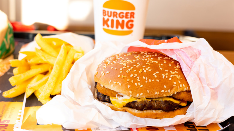 Burger King cheeseburger with fries and a drink served on a table