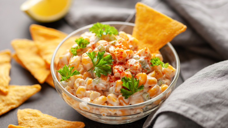 Mexican-style street corn in a small glass bowl with tortilla chips
