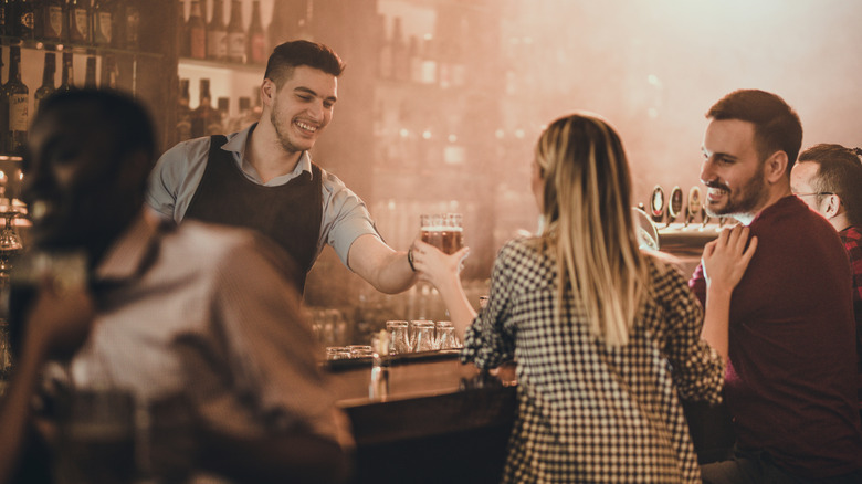 bartender hands drink to patron