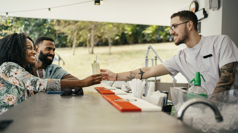 bartender handing drink to woman at outdoor bar