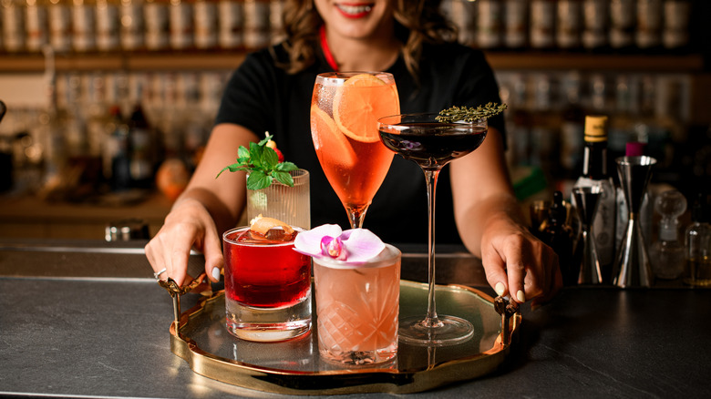 bartender holds tray with varied cocktails