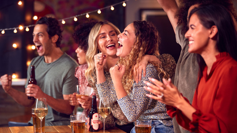 friends at bar drinking beer and celebrating sports game