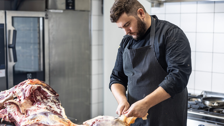 A butcher wears an apron while preparing meat