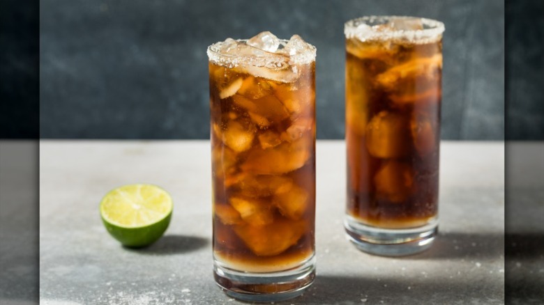 Two highballs with coke, salted rims, next to cut lime