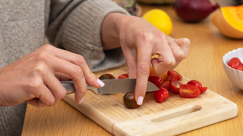 Woman cutting cherry tomatoes with a paring knife