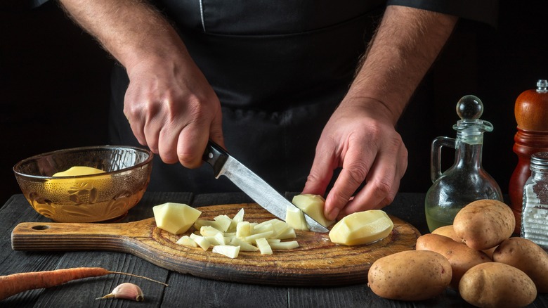 Someone cutting a potato with a paring knife