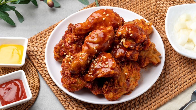 Korean fried chicken covered in sauce on white plate
