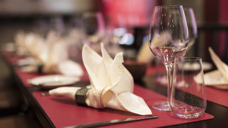 White linen napkin on a red table placemat with wine glasses