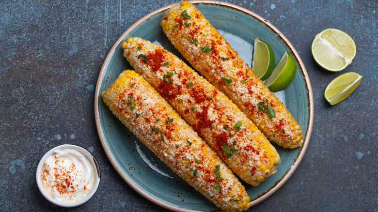 elotes with lime wedges and sour cream