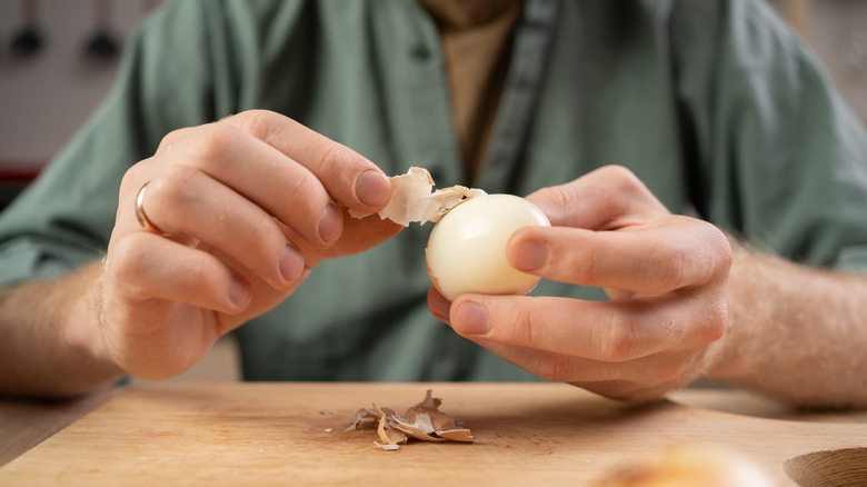 Man's hands peeling boiled egg
