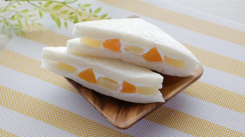 A Japanese fruit sandwich sliced diagonally on a small wooden tray
