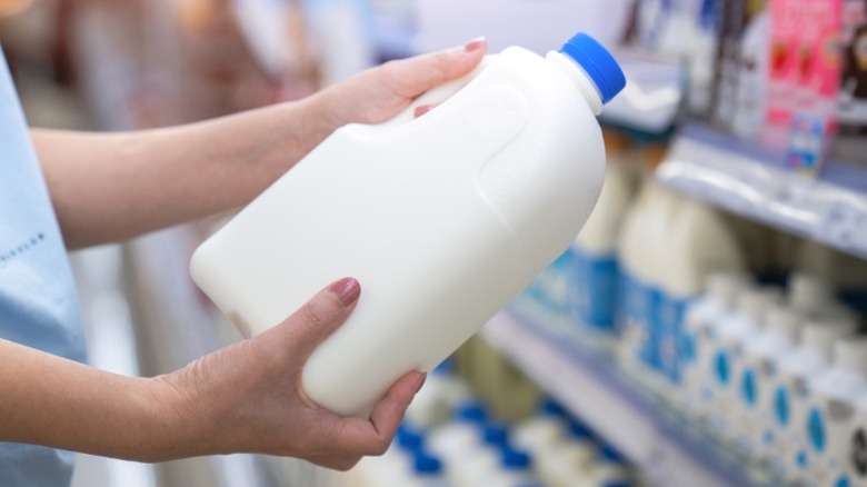 A woman choosing milk at the supermarket.
