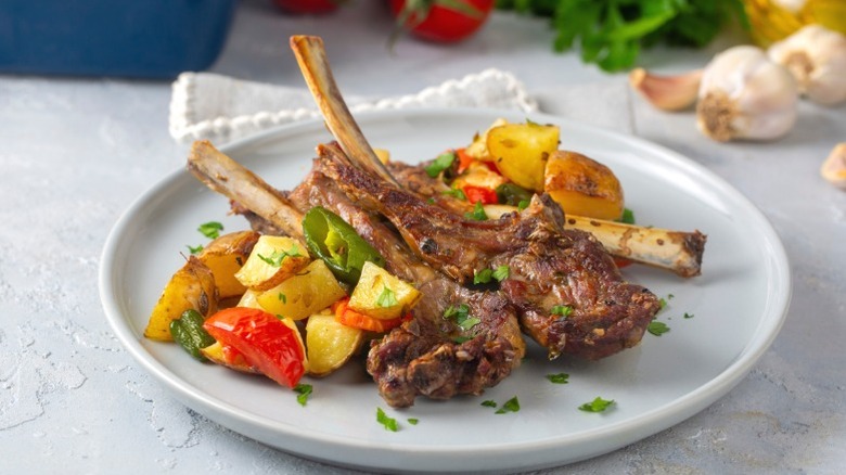 Marinated lamb chops on a plate with vegetable sides.