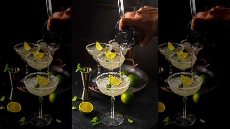 A bartender pours a margarita into a glass