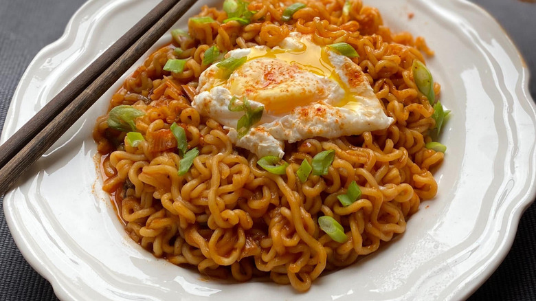 cat sniffing ramen on plate
